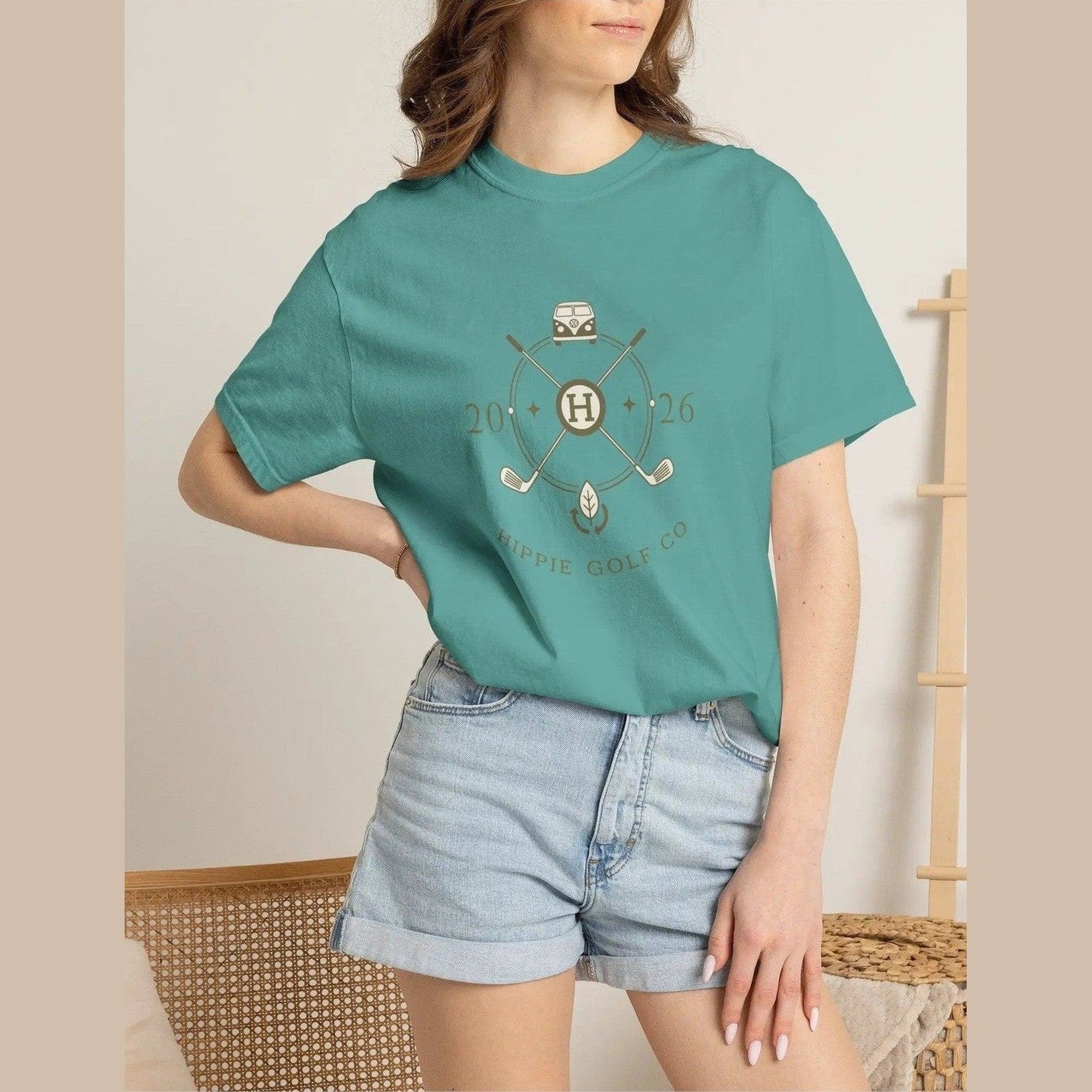 Teal unisex t-shirt on model paired with denim shorts and retro golf club logo