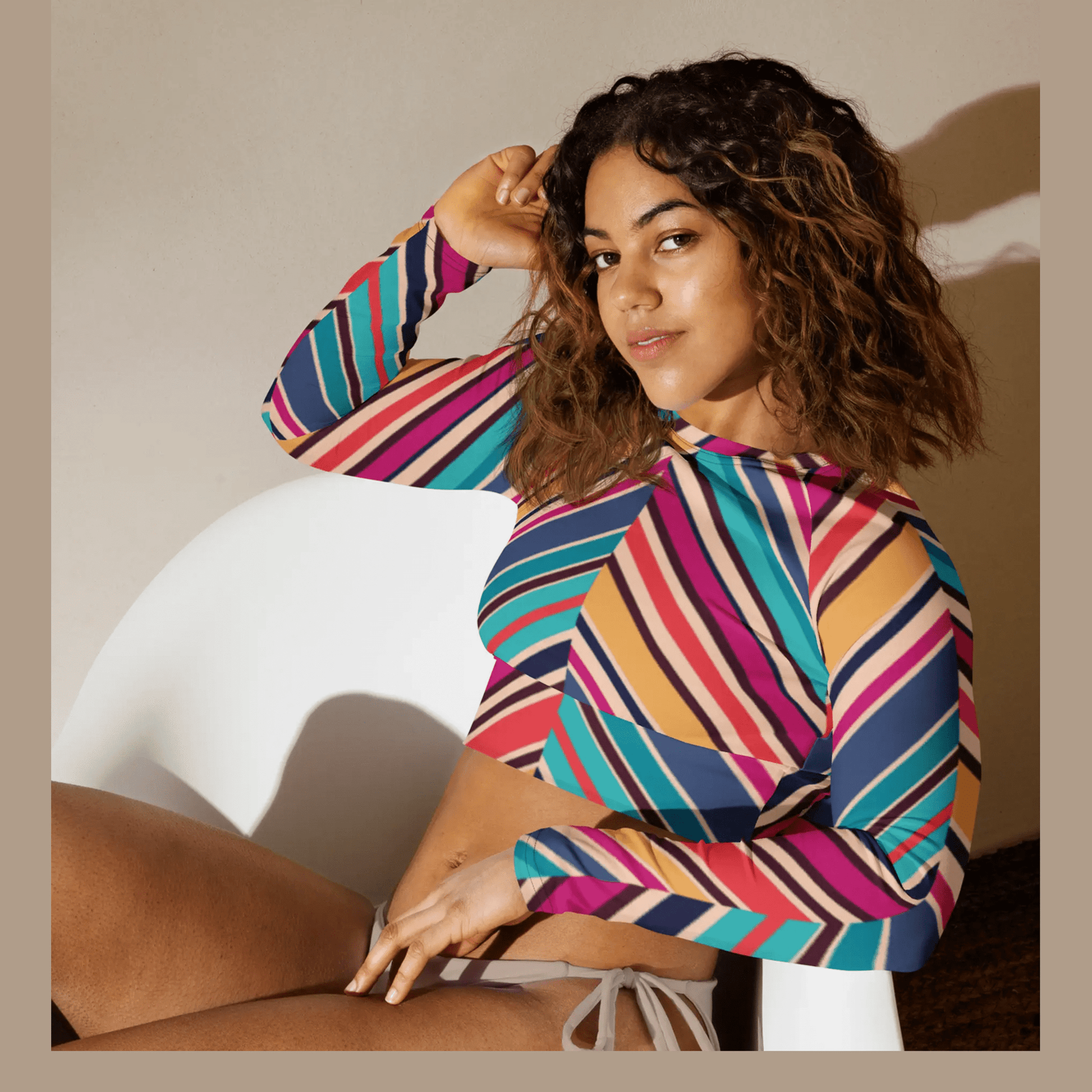 Form-fitting multicolor striped long-sleeve crop top worn by woman sitting