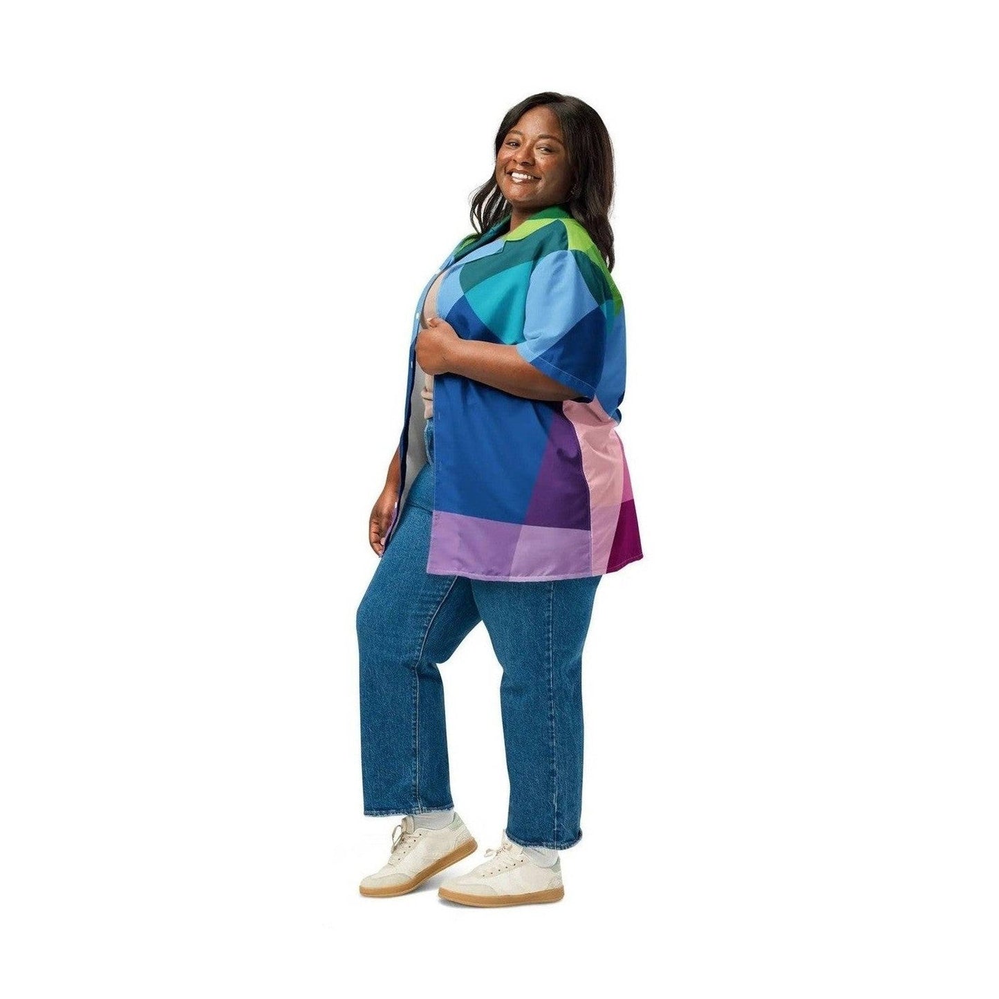Woman wearing oversized abstract button shirt open over white top and blue jeans