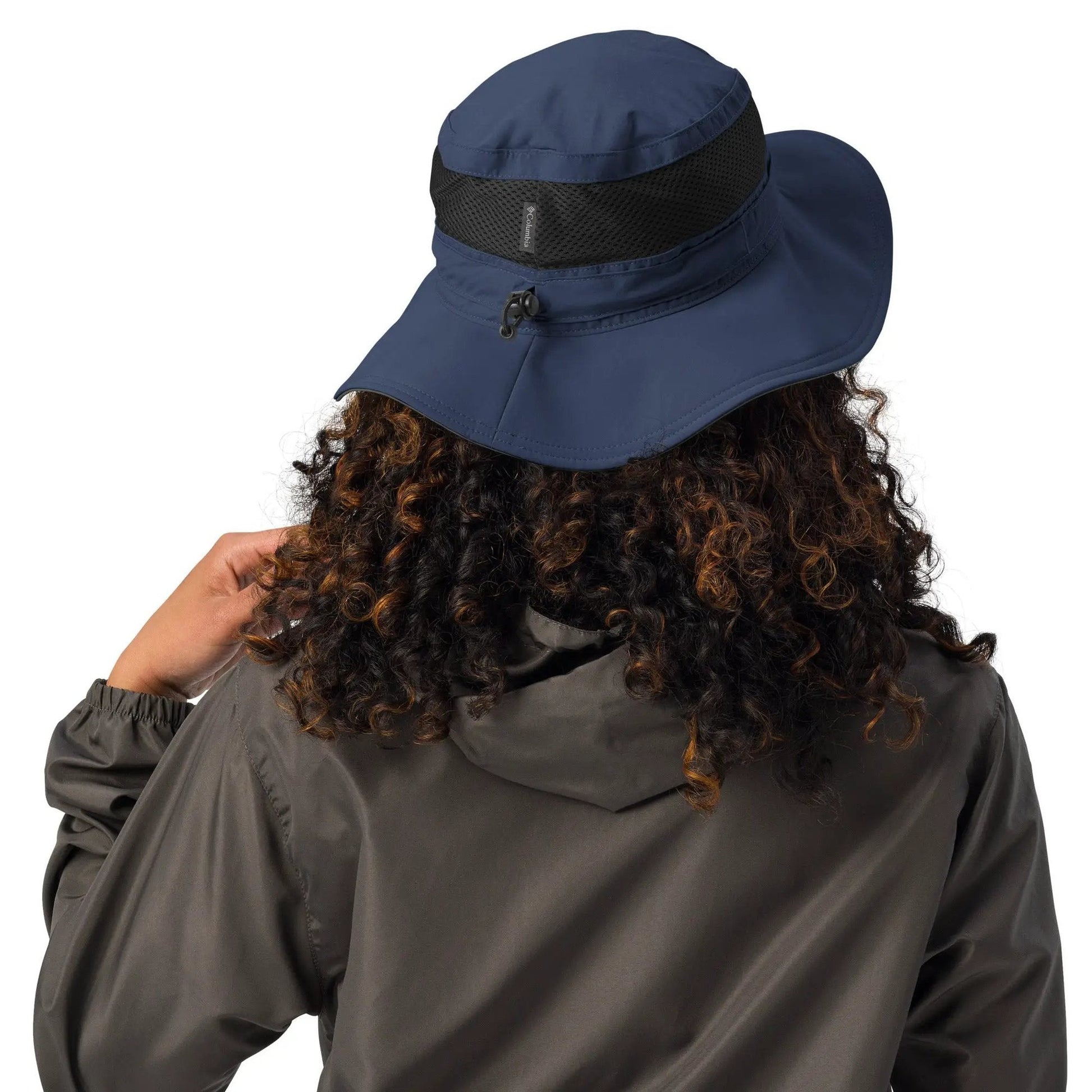 Rear view of person wearing navy booney hat with back mesh panel and chin strap toggle