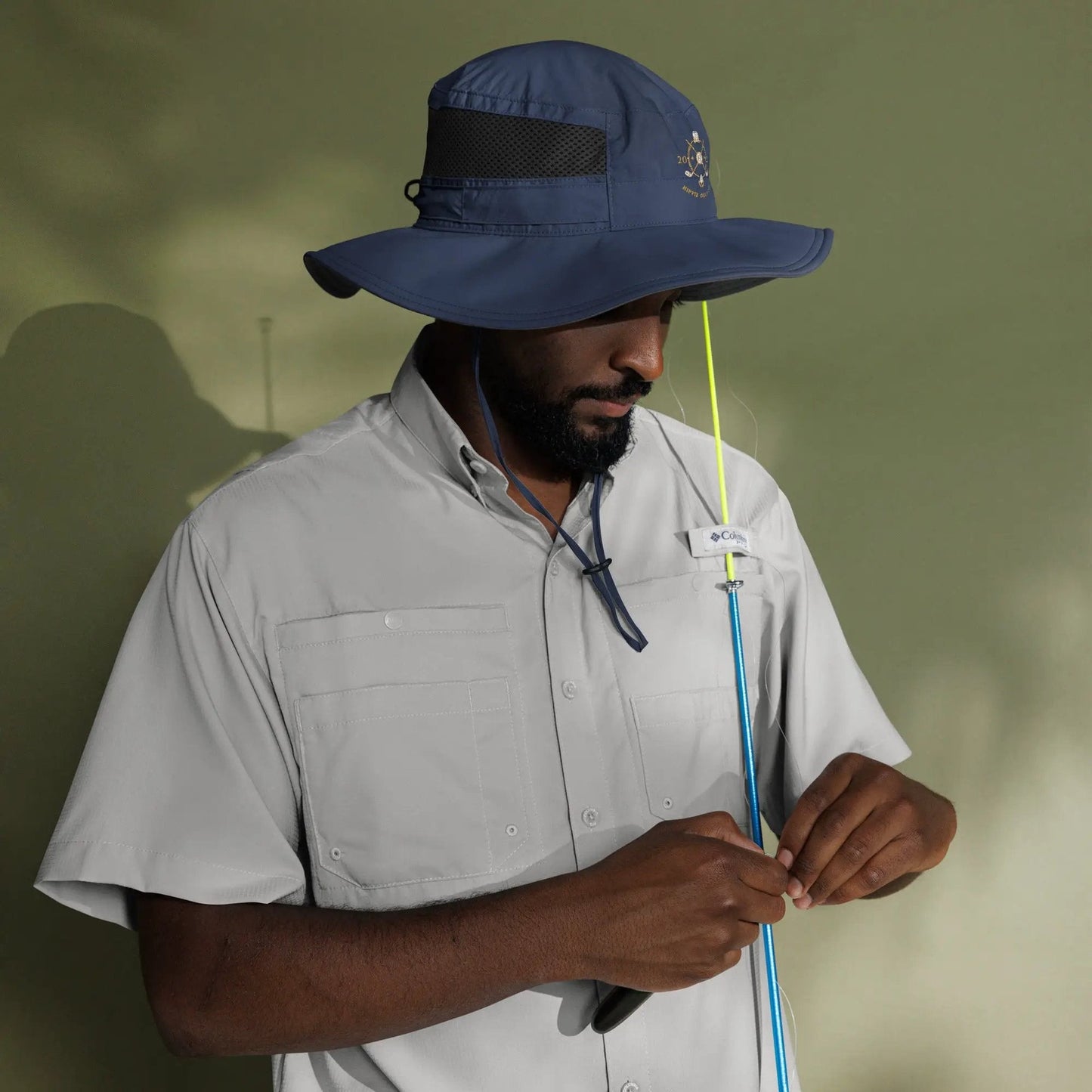 Model holding fishing rod while wearing navy booney hat for outdoor sun protection