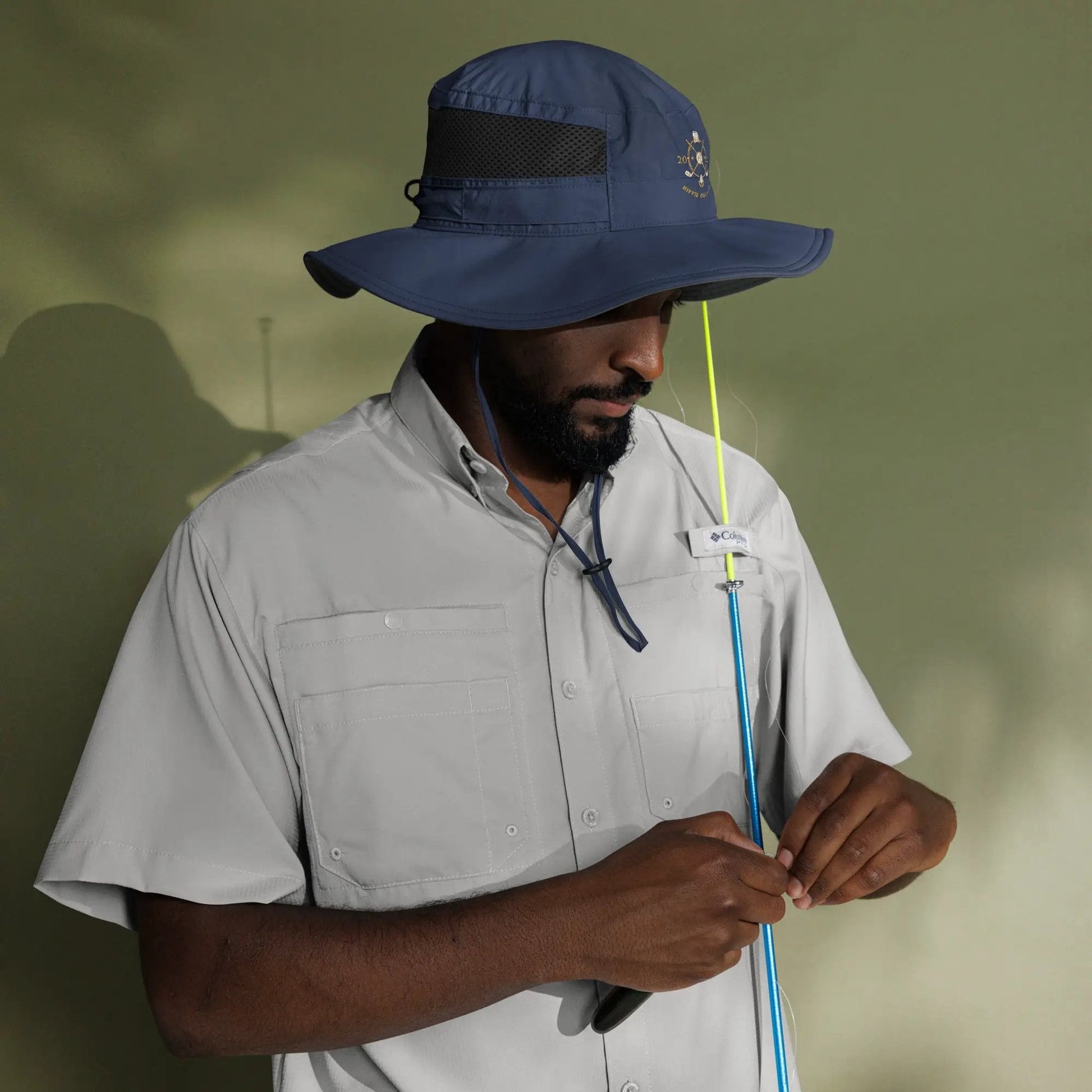 Model holding fishing rod while wearing navy booney hat for outdoor sun protection
