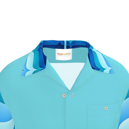 A close-up of a light blue short-sleeve button-up shirt with a patterned collar in shades of blue and teal, featuring a visible 'Hippie Golf Co' neck label.
