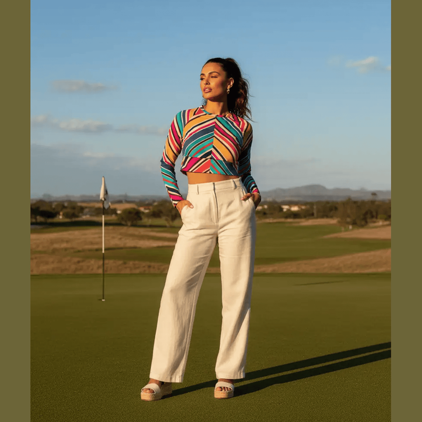 Woman wearing multicolor diagonal stripe long-sleeve crop top with rounded neckline and wide waistband