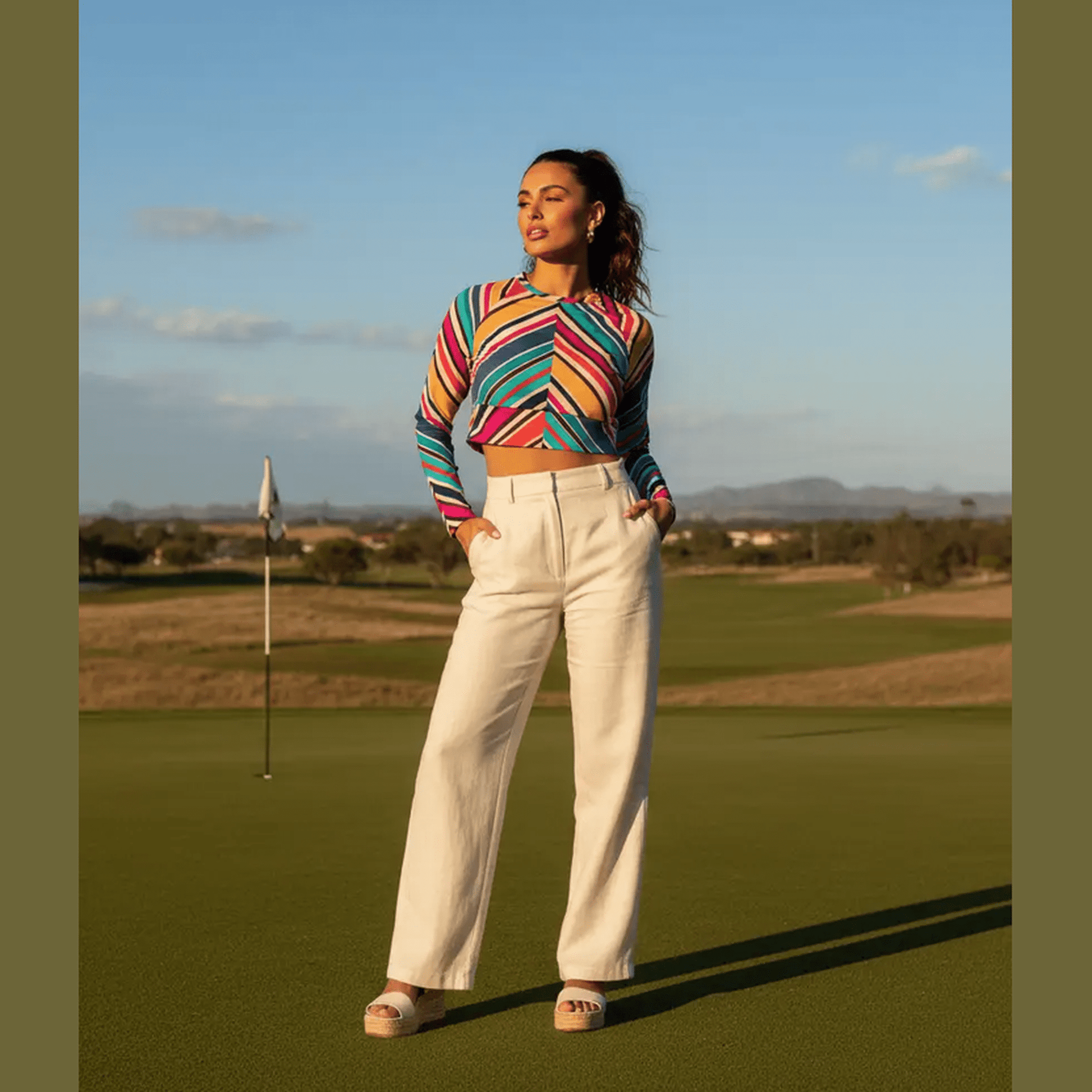 Woman wearing multicolor diagonal stripe long-sleeve crop top with rounded neckline and wide waistband