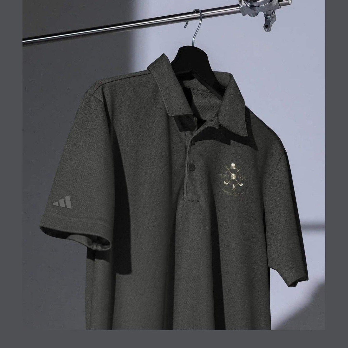 Hanging dark gray Adidas Space-Dyed Pro polo displaying collar, placket, and embroidery